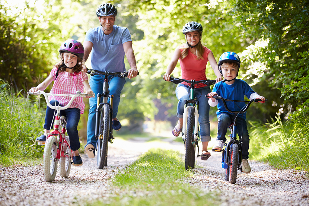 Rodzina z dziećmi na rowerach jadąca szlakiem przez las